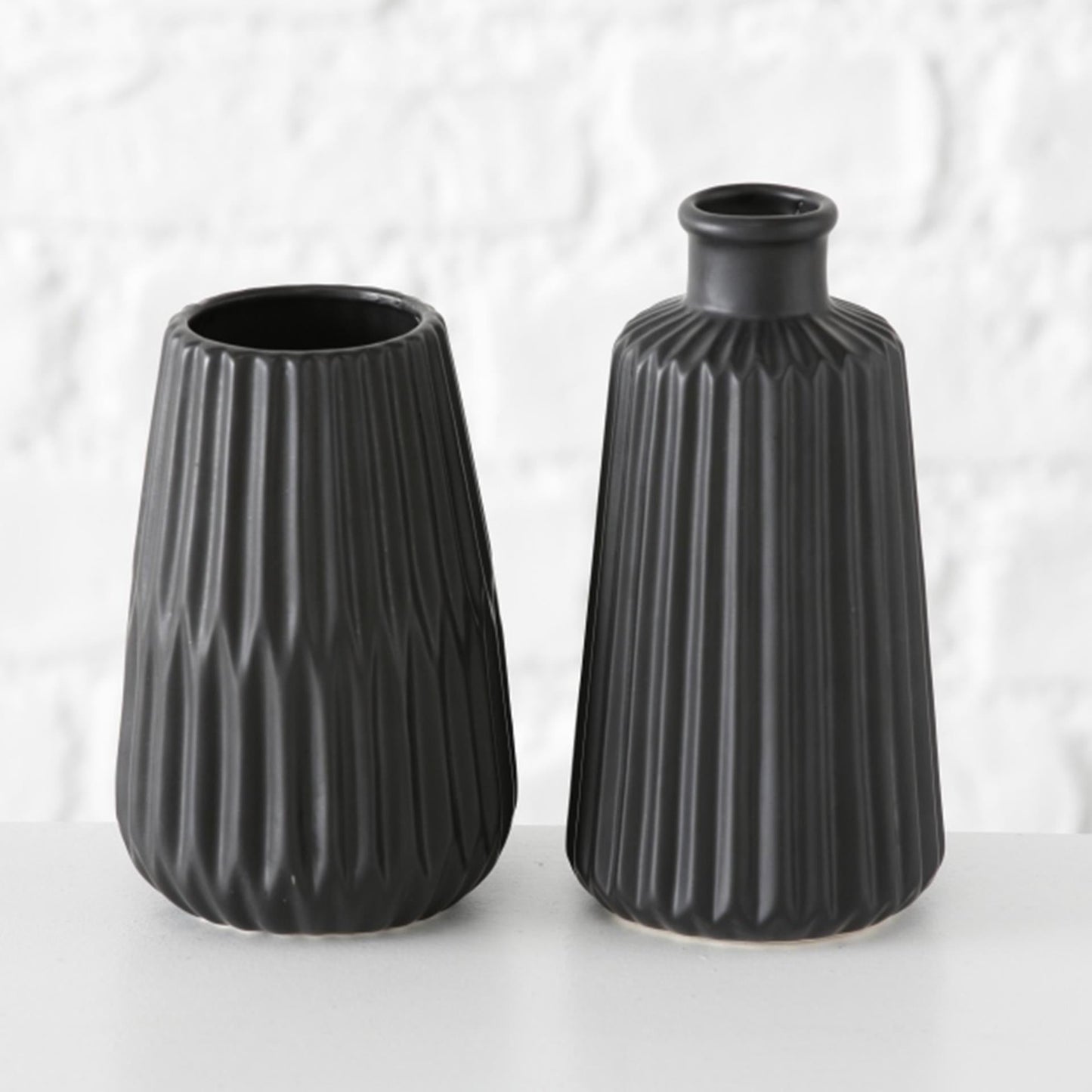 The Boltze Home Vase Esko in black porcelain, placed on a wooden table, holding a small bouquet of flowers