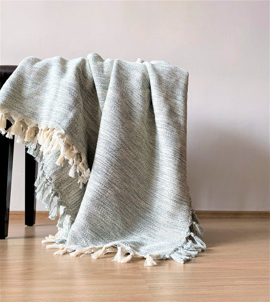 The Adana handwoven cotton cover in natural tones, hung on a wall in a living room