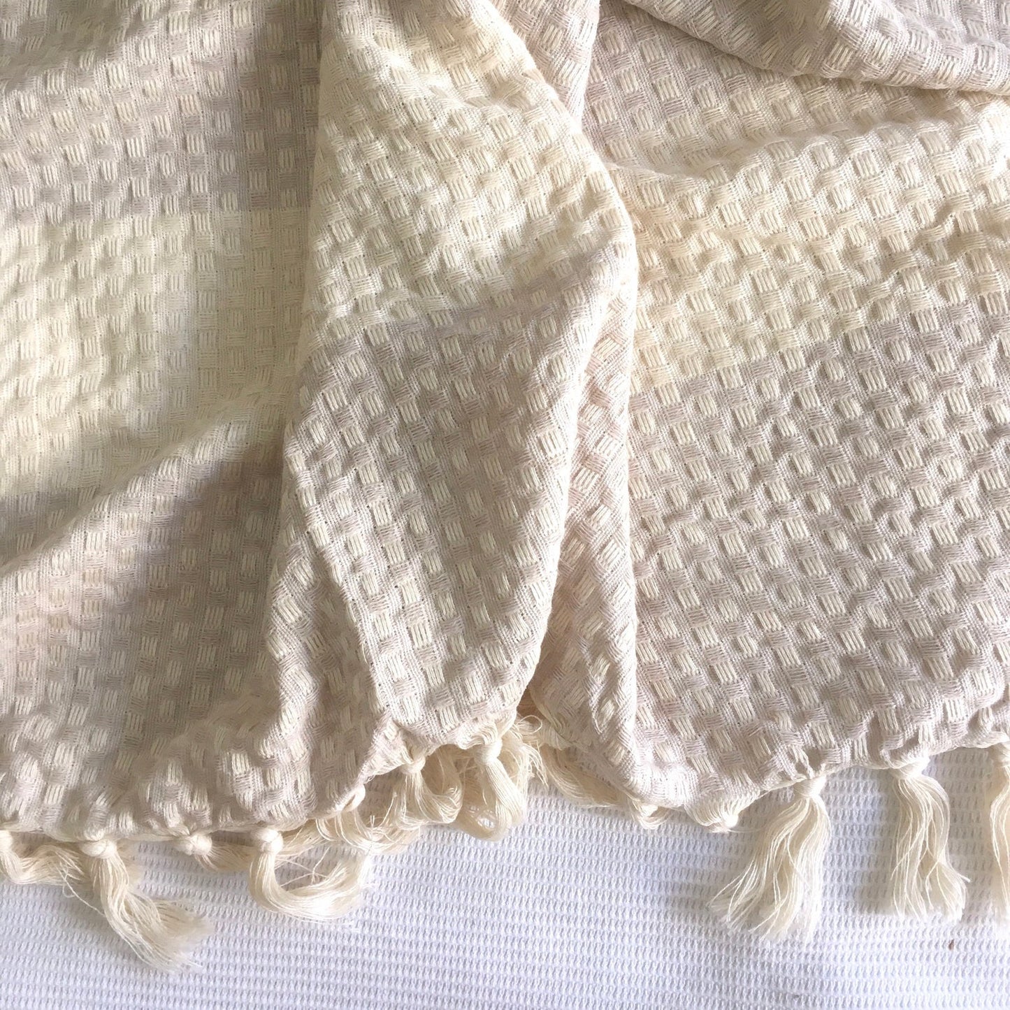 The Istanbul Handwoven Cotton blanket draped over a couch armchair